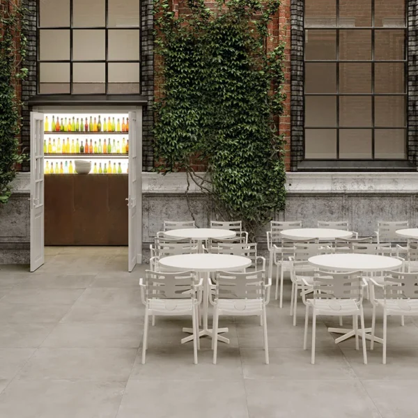 Gresie porțelanată Materia de la Ceramiche Piemme, culoarea Nacre, montată pe terasa unei curți exterioare cu mese de bistro