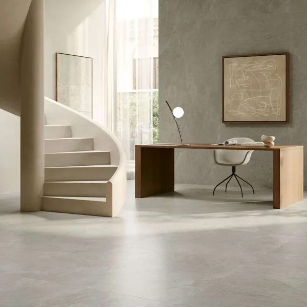Minimalist home office with a curved beige spiral staircase beside a wooden desk, white chair, and tall plant in a bright room.
