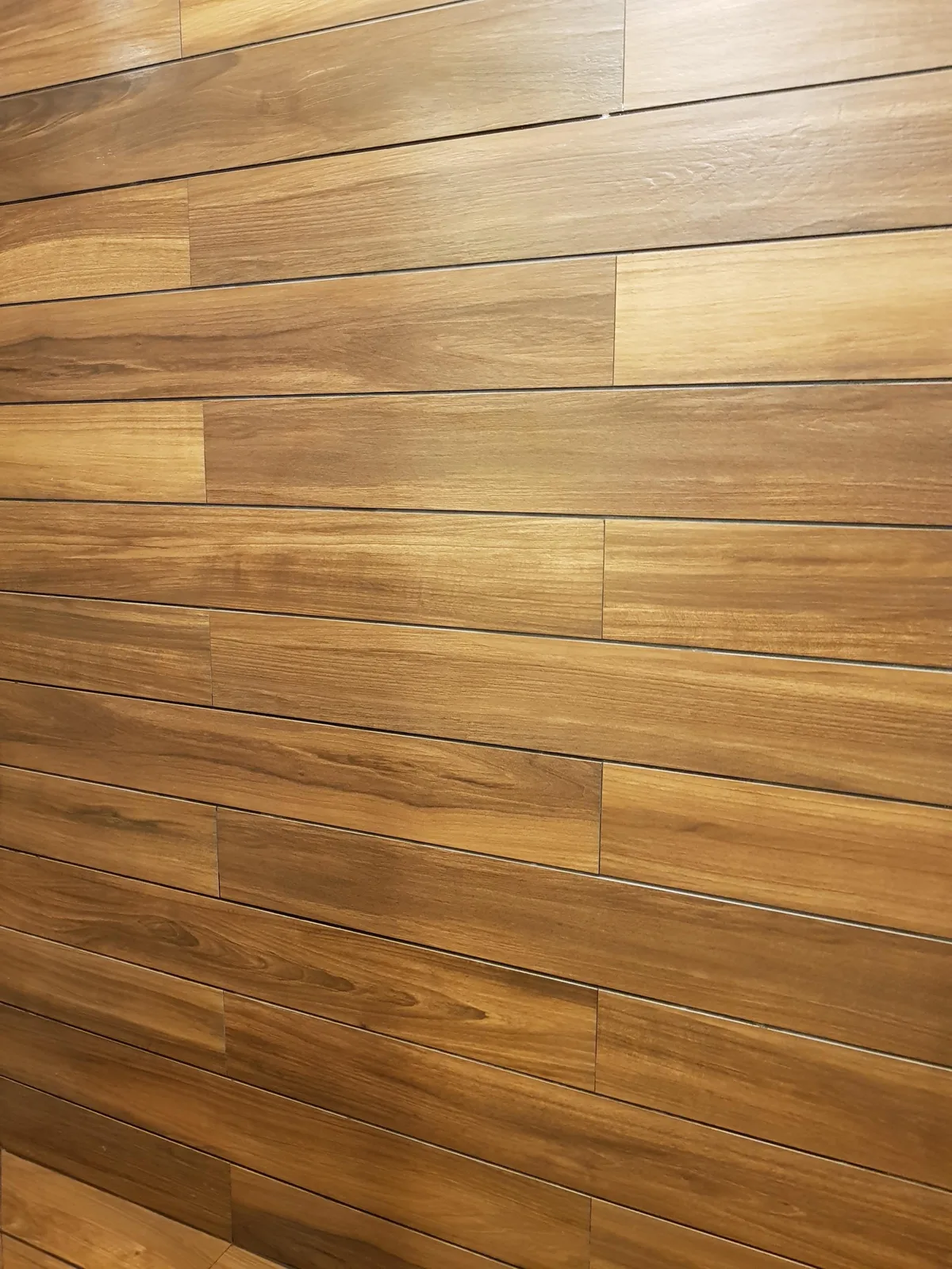 Perete placat cu lamele ceramice aspect lemn, văzut în lumină razantă