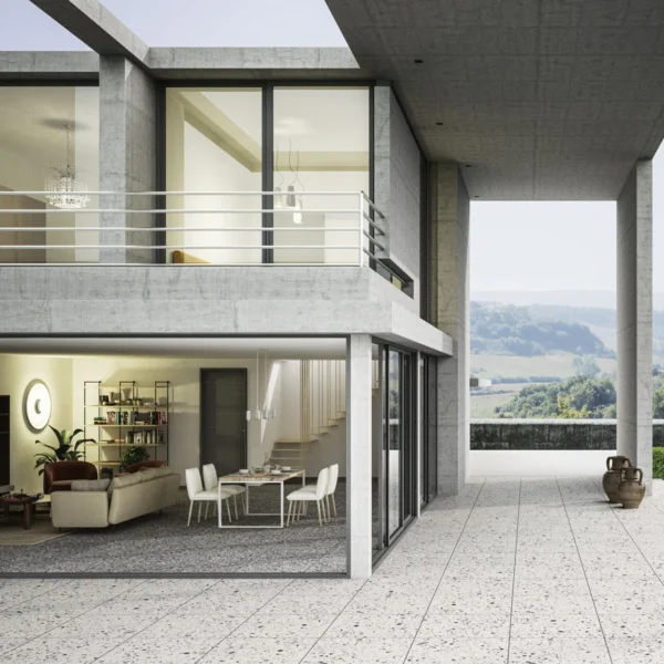 Modern two‑story house with large glass walls; open living and dining area seen from the outside, plus a wide tiled terrace with concrete columns and a distant landscape view.